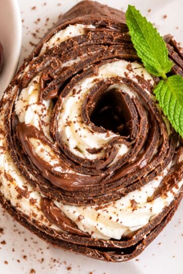 Chocolate crepe roll with layers of whipped cream and Nutella, served with fresh cherries and mint.