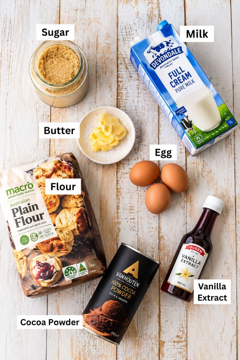 Ingredients for homemade chocolate crepes, including flour, cocoa powder, eggs, milk, butter, sugar, and vanilla.