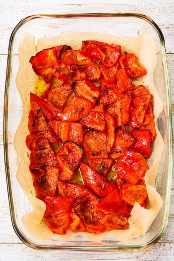 Close-up of roasted red bell peppers with lightly charred edges, coated in olive oil and smoked paprika.