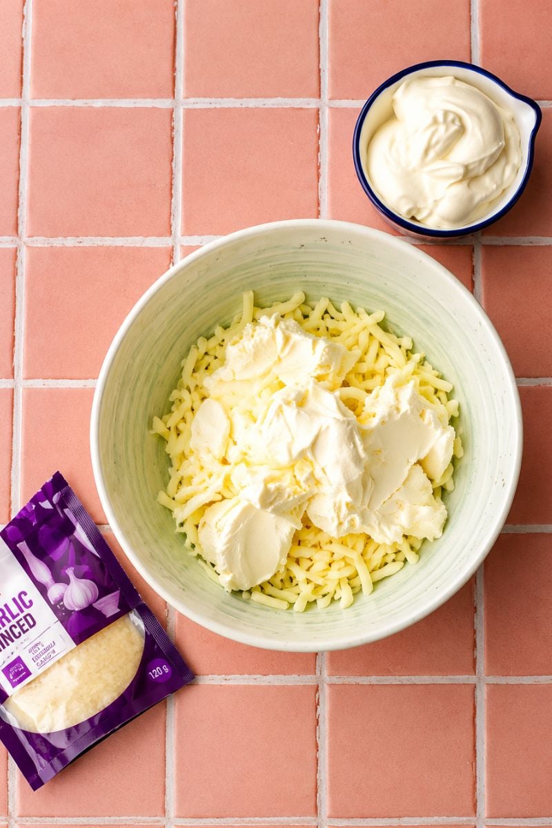 Cream cheese, shredded cheese, and seasonings in a mixing bowl for homemade spinach dip.
