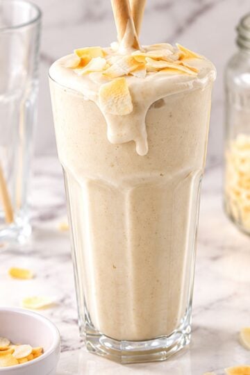 Creamy coconut shake with toasted coconut flakes in a tall glass.