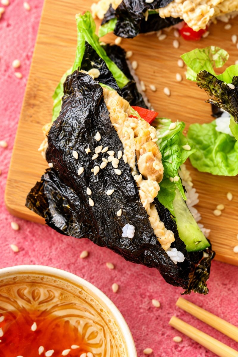 Vegetarian sushi wrap with creamy chickpea filling, fresh lettuce, and dipping sauce.