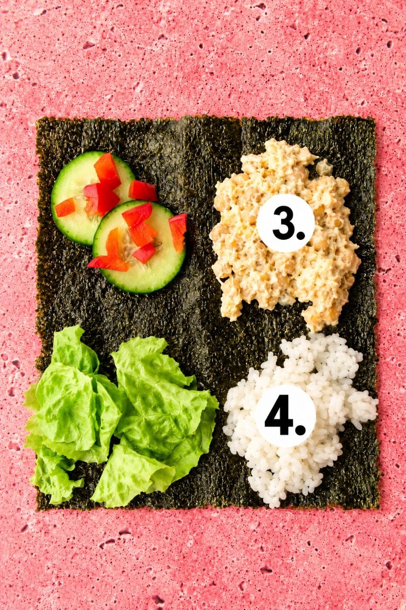 Cooked sushi rice added alongside chickpea filling, cucumber, and lettuce on a nori sheet.