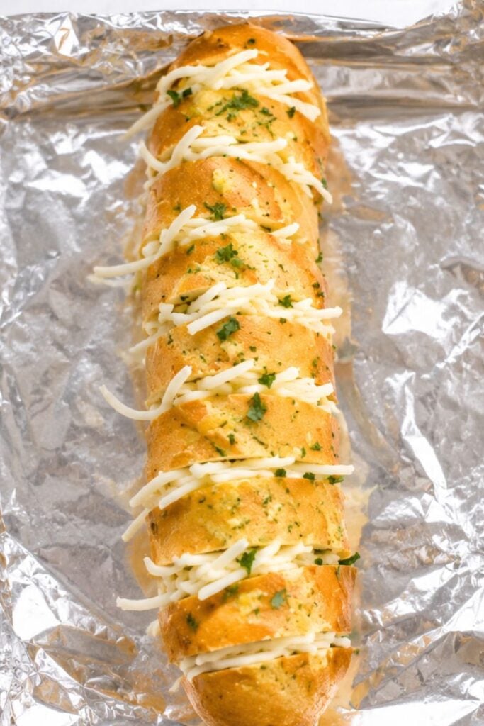 Shredded mozzarella cheese stuffed between the slices of a French baguette before baking.