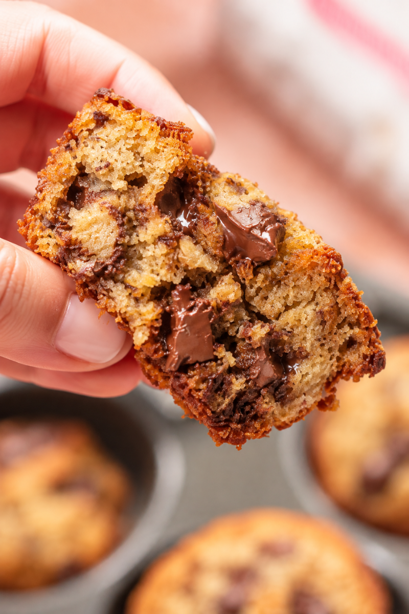Banana chocolate chunk muffin broken open to show its soft crumb and chocolate pieces.