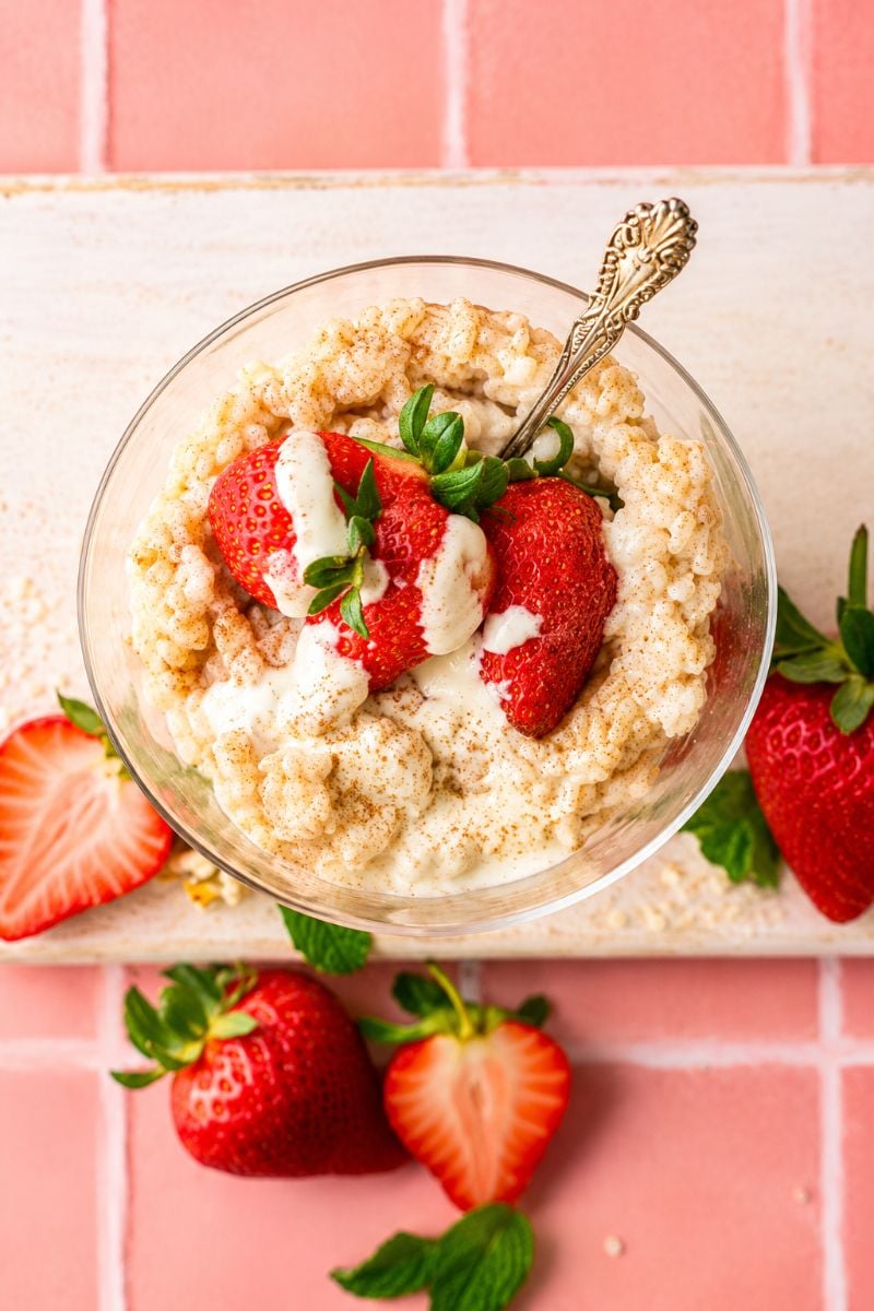 Homemade vanilla protein rice pudding with juicy strawberries and a drizzle of cream.