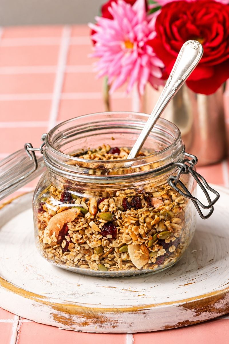 Crunchy homemade sugar free granola with oats, nuts, seeds and dried cranberries stored in a glass jar.