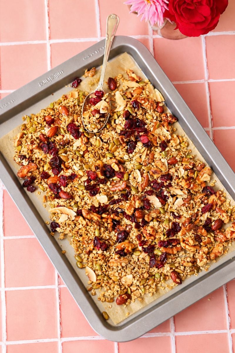 Golden homemade sugar free granola with toasted oats, nuts, coconut flakes and dried cranberries on a baking tray.