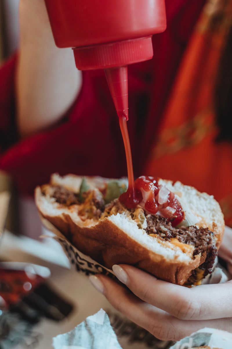 Pouring ketchup onto a burger. This recipe is a great substitute for ketchup.