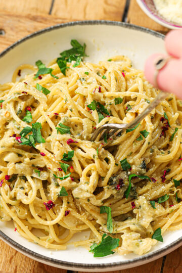 A bowl of caramelized onion pasta with a side parmesan cheese on the side.