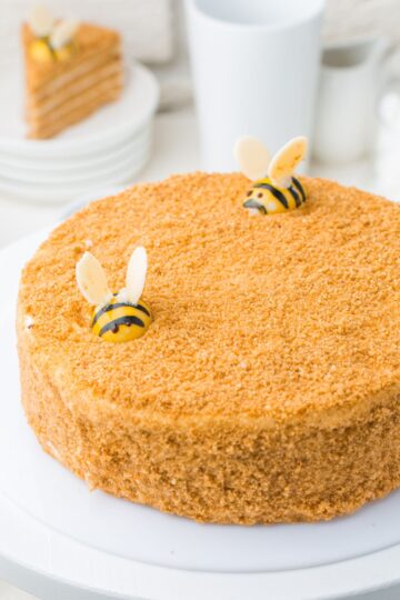 A honey cake with edible bumble bees placed on the top of the cake.