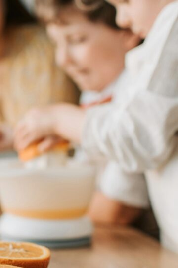 Young children squeezing an orange. Here are 10 substitutes for orange juice.