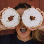 How to soften cream cheese quickly. A lady holding two bagels with cream cheese in front of her eyes.