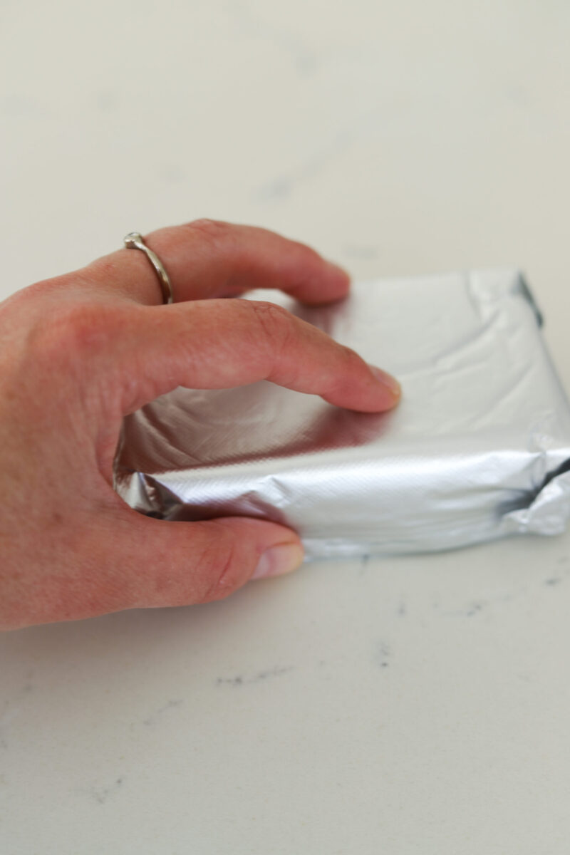 A hand on top of the cream cheese.