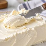 Softened cream cheese being spread with a knife