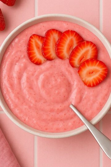 A strawberry smoothie bowl with a few strawberries on the top.