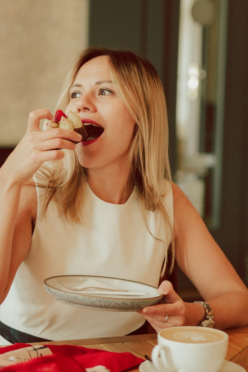 A lady eating a chocolate brownie. 