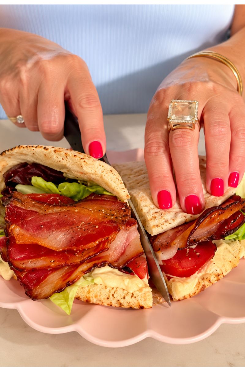 Close-up of hummus pita filled with crispy bacon, lettuce and tomatoes