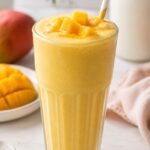 A mango milkshake with chopped mango on the top .