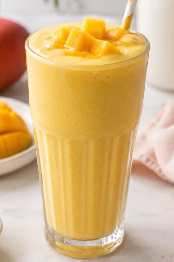 A mango milkshake with chopped mango on the top .