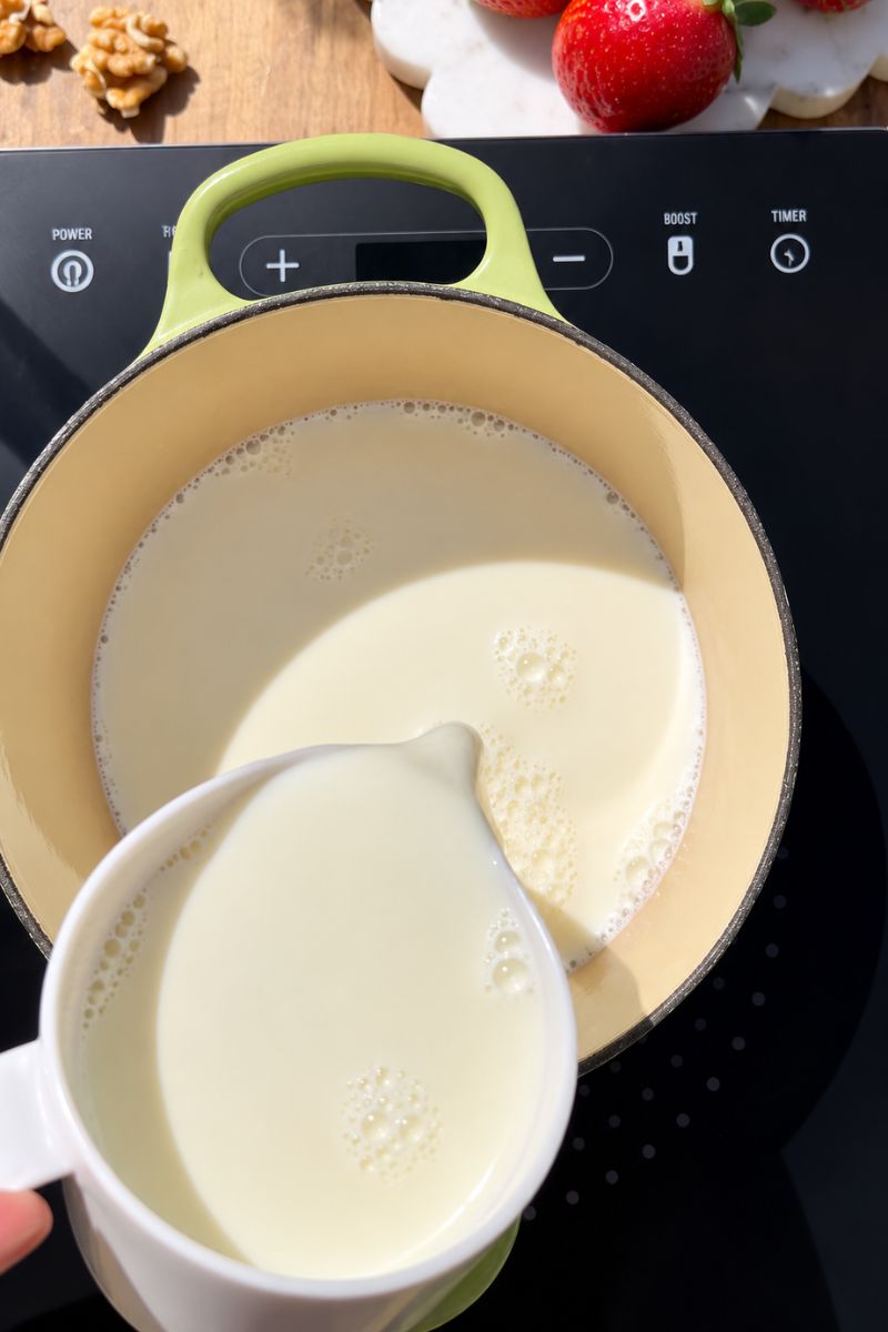 Adding milk to a saucepan. 