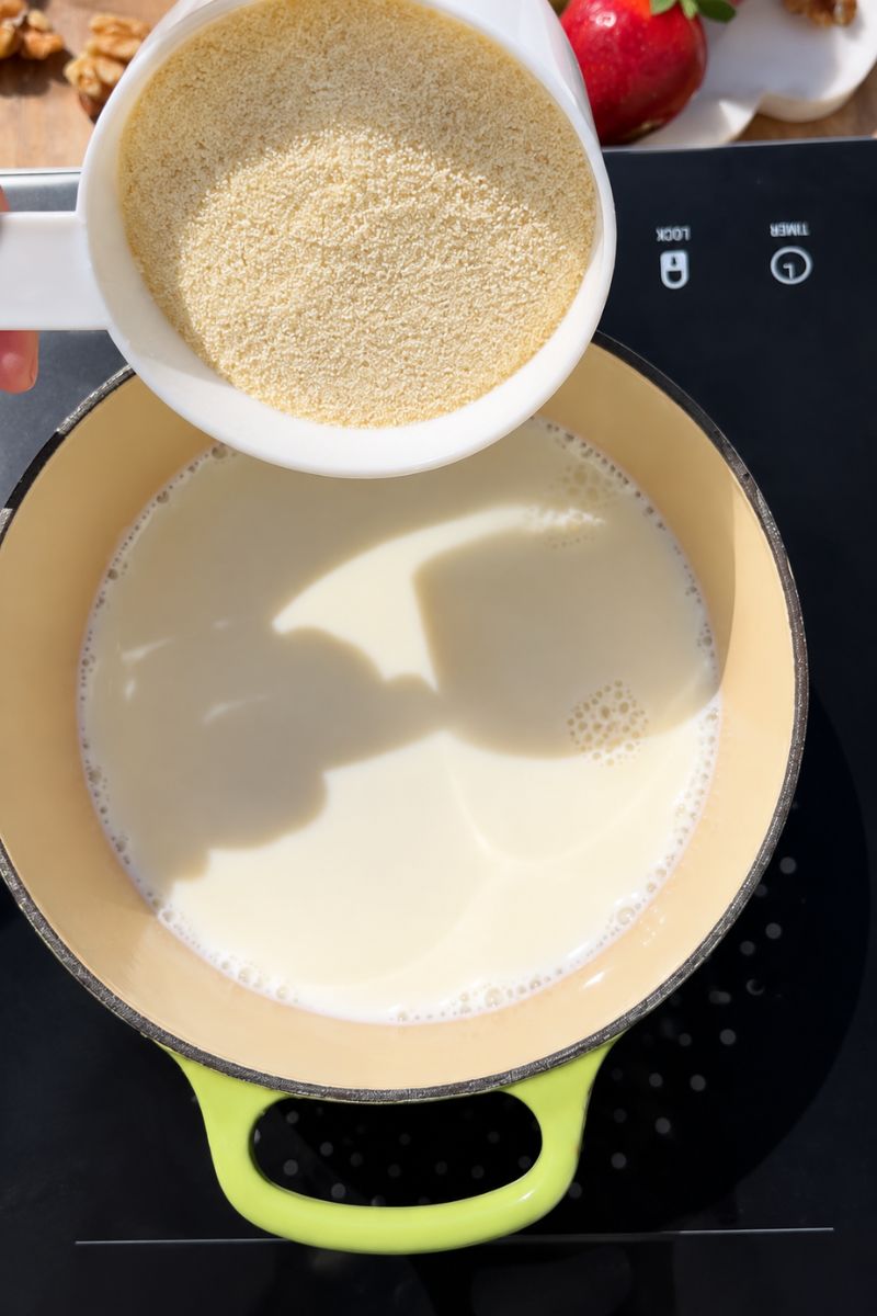 Adding semolina to the warm milk. 