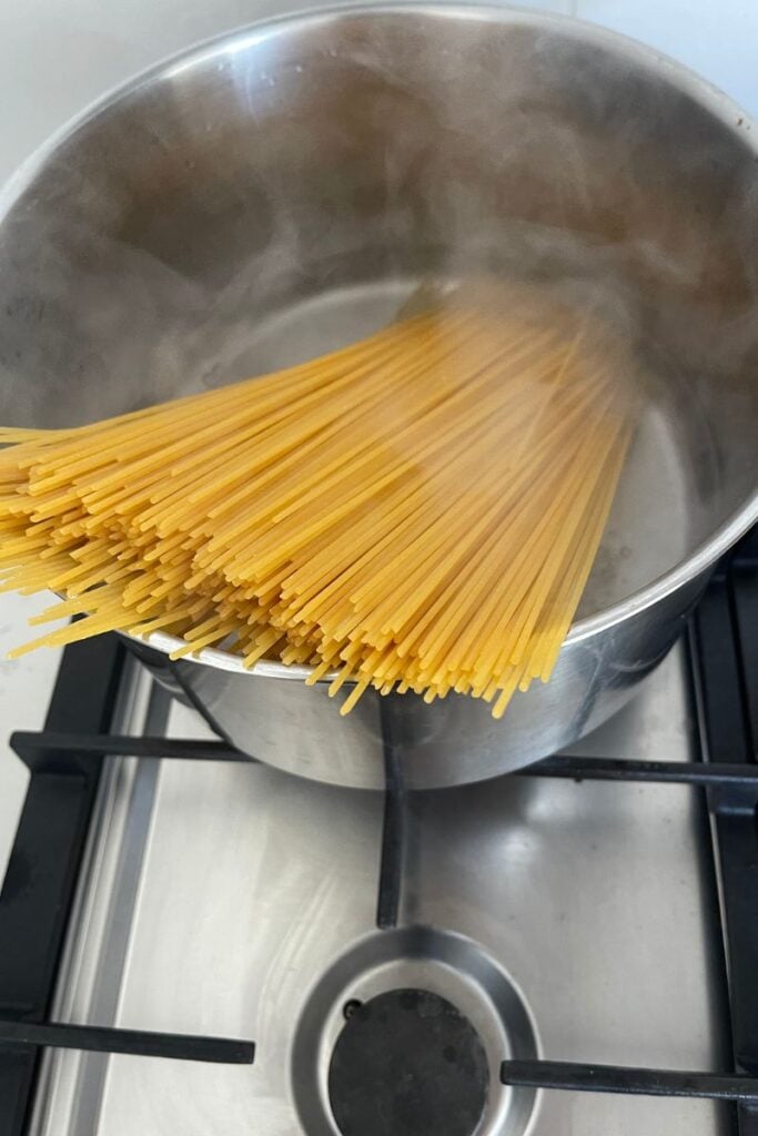 Spaghetti cooking in a pot of boiling water for garlic butter shrimp pasta.