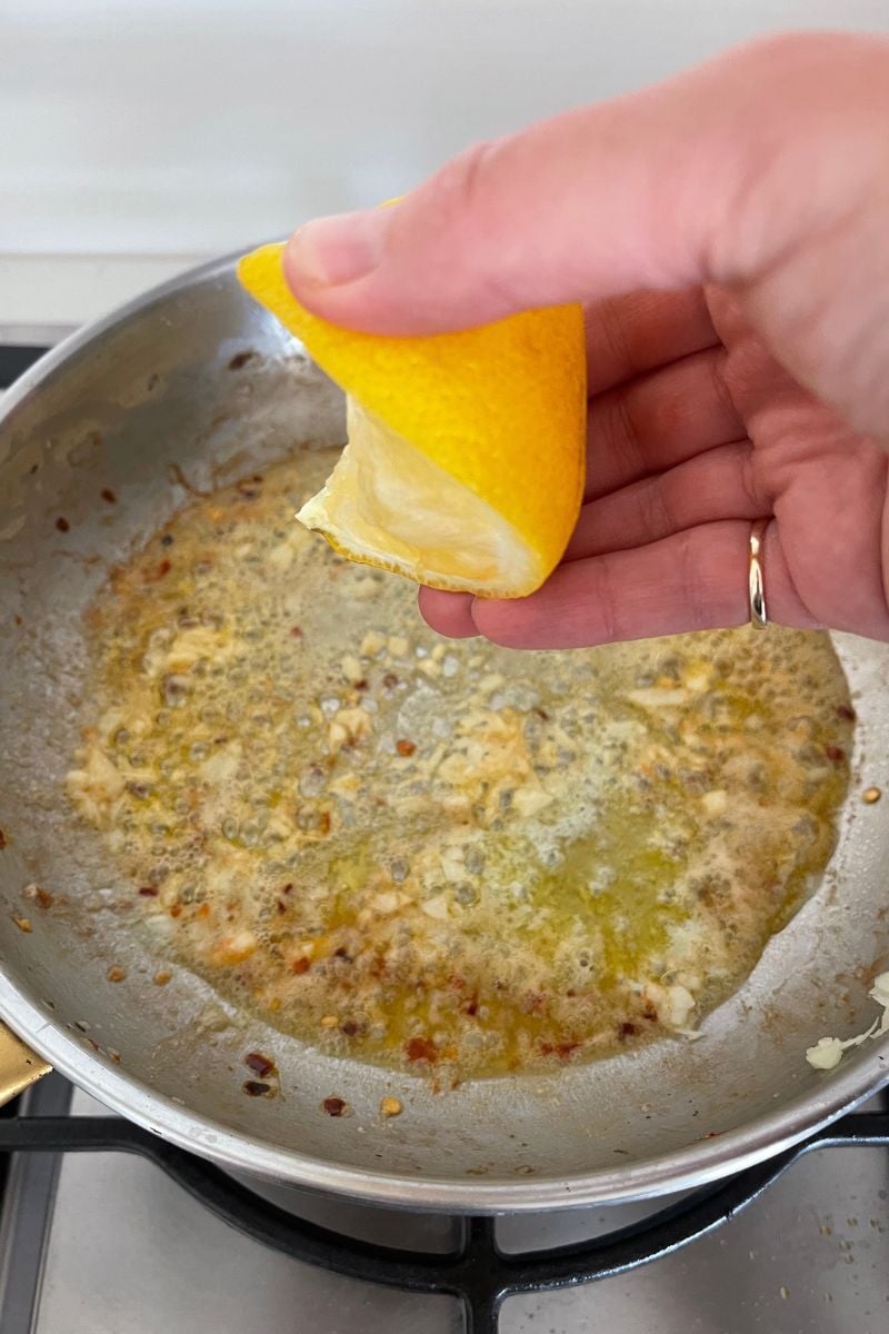Creamy garlic butter sauce with lemon and Parmesan cooking in a frying pan.