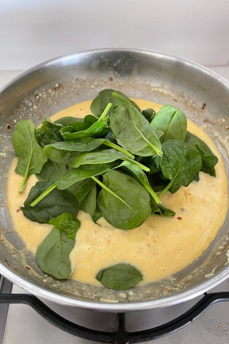 Adding spinach to the sauce.