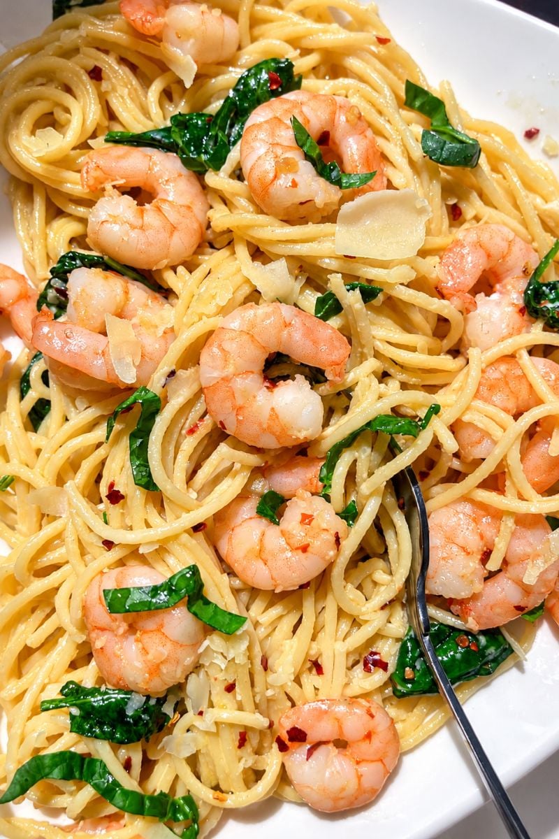 Close-up of creamy garlic butter shrimp pasta with spaghetti, spinach, Parmesan and red pepper flakes.
