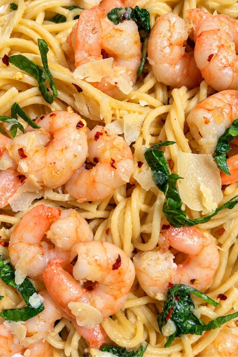 Close-up of creamy garlic butter shrimp pasta with spaghetti, spinach, Parmesan and red pepper flakes.