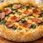 bacon and cheese quiche on a wooden chopping board.