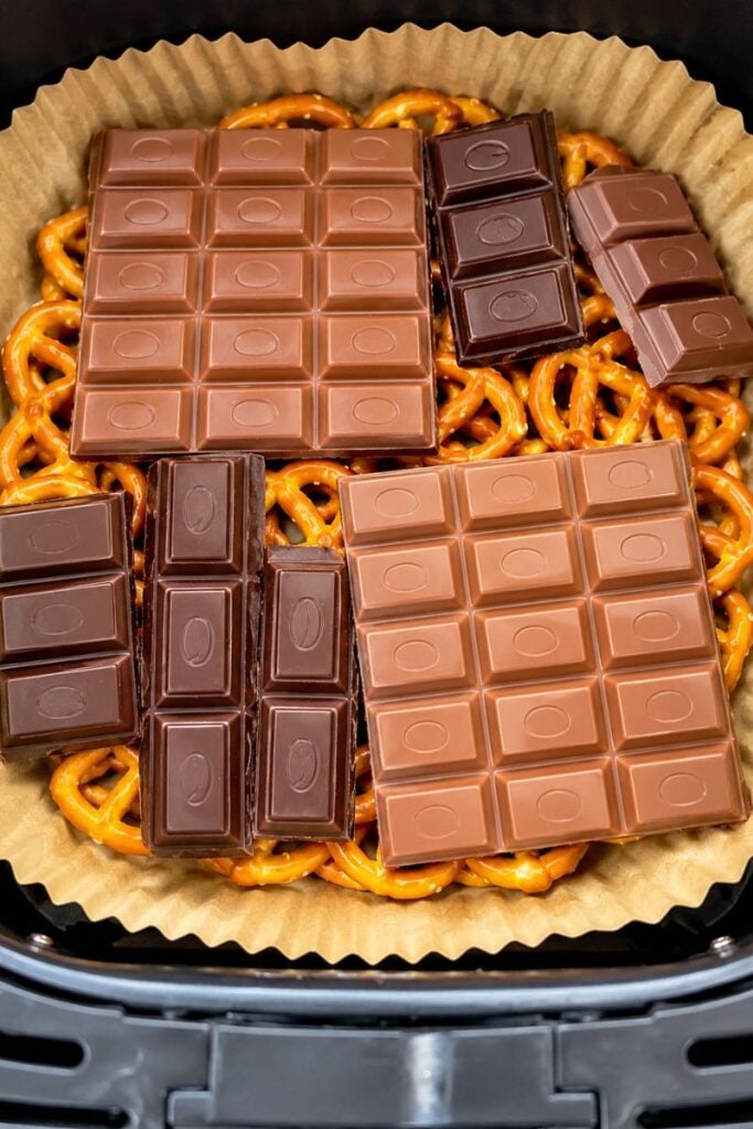 Milk and dark chocolate layered over pretzels in a lined air fryer