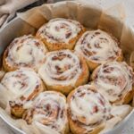 Easy no-rise cinnamon buns in a round container with cream cheese frosting.