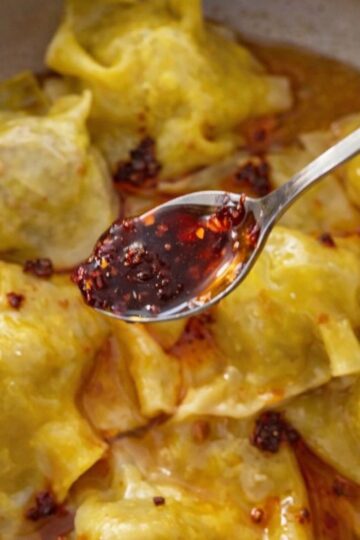 pan fried dumplings with mince meat in a pan with chili oil and sesame seeds.