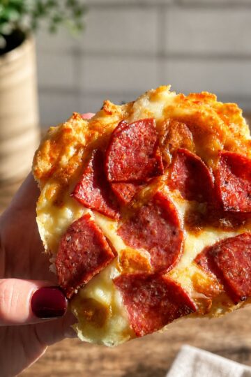 Holding a small pizza with pepperoni. The base is made with 2 ingredient pizza dough.