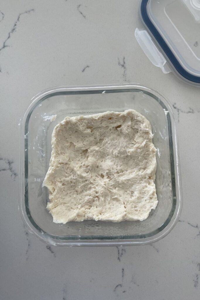 Pizza dough in a small glass container. 