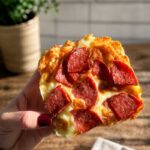 Holding a small pizza with pepperoni. The base is made with 2 ingredient pizza dough.