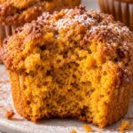 Pumpkin muffin with a bite showing the soft fluffy center.