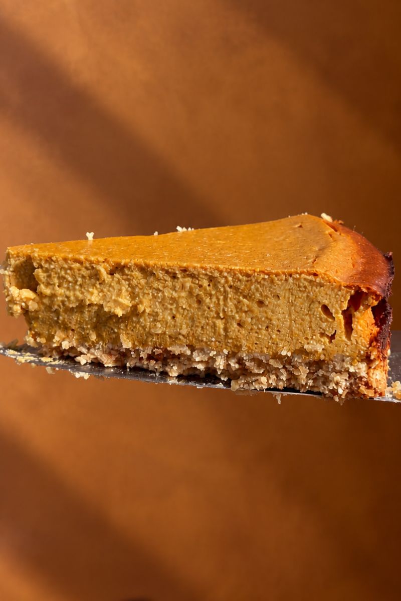 Slice of healthy pumpkin cottage cheese cheesecake showing the creamy pumpkin filling.