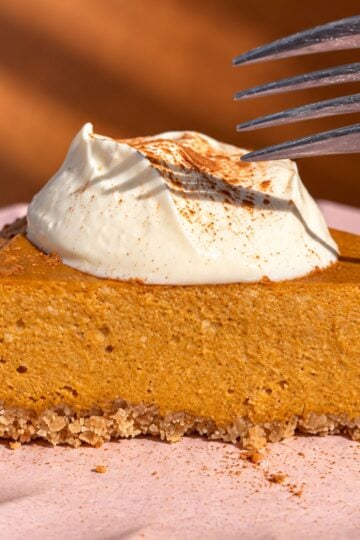 Slice of pumpkin cottage cheese cheesecake topped with Greek yogurt and cinnamon.