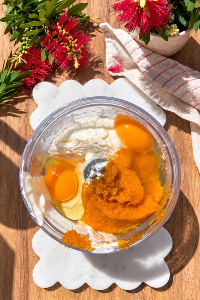 Ingredients in blender: Pumpkin cottage cheese cheesecake ingredients with pumpkin puree, cottage cheese, Greek yogurt and eggs.