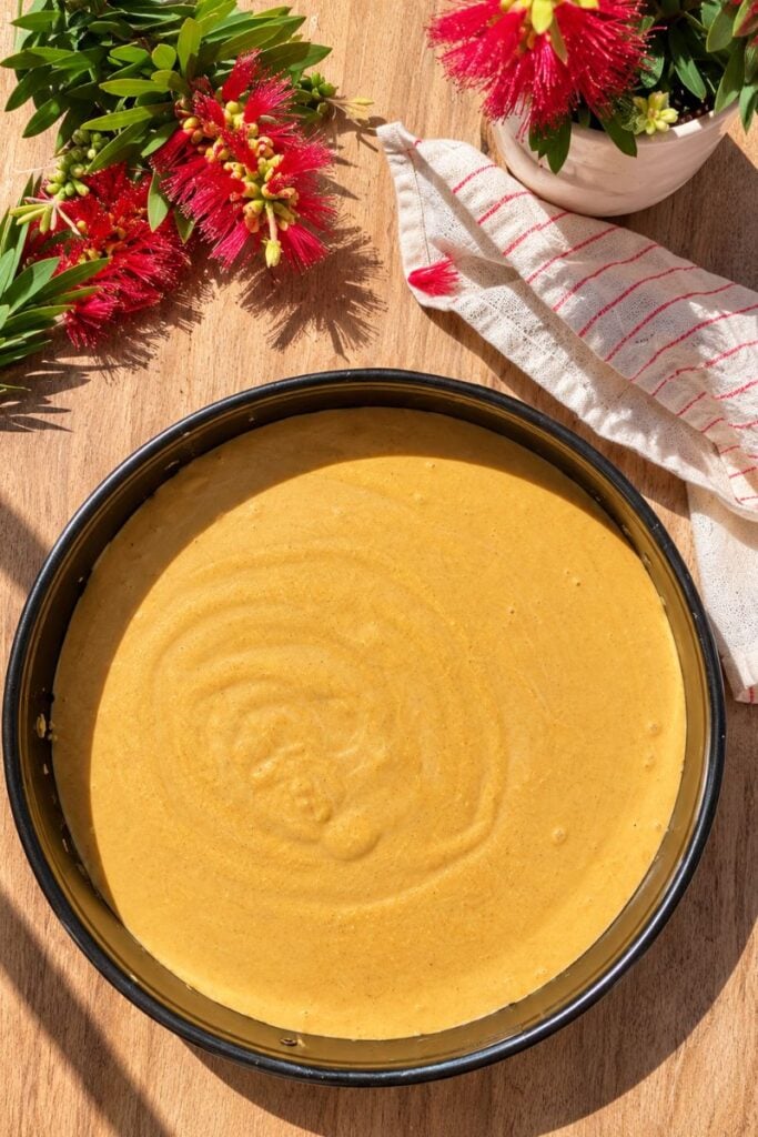 Pumpkin cottage cheese cheesecake filling poured over the oat crust before baking
