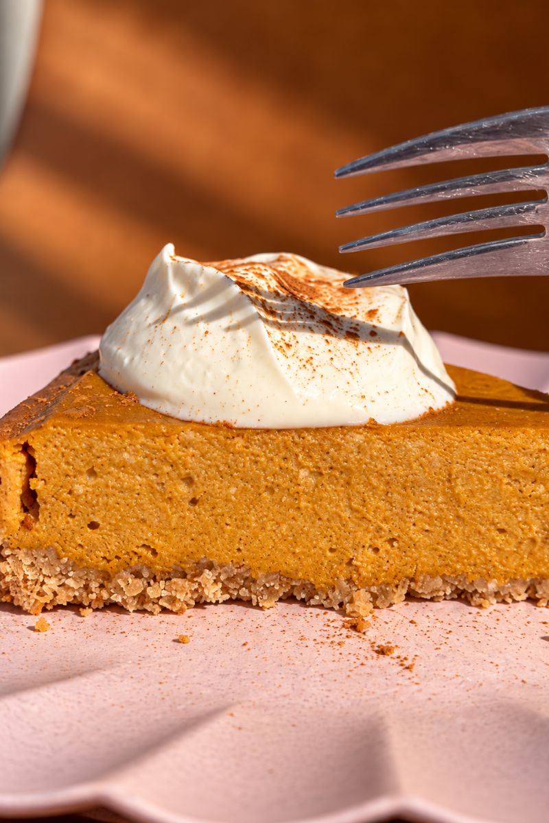 Slice of pumpkin cottage cheese cheesecake topped with Greek yogurt and cinnamon.