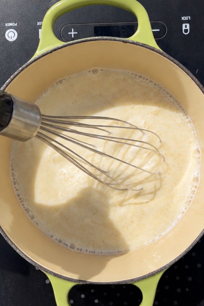 Semolina pudding being whisked on the stovetop until smooth and creamy