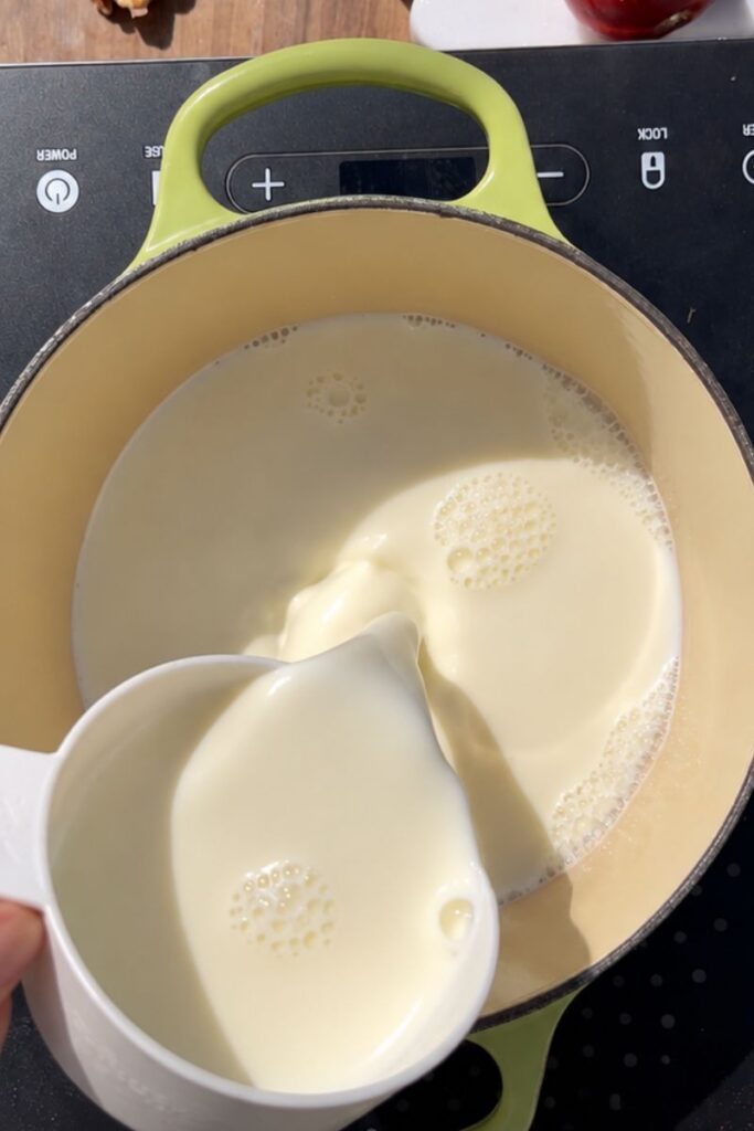 Whole milk heating in a saucepan for homemade semolina pudding.